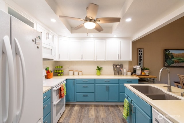 kitchen featuring sink, white cabinetry, a tray ceiling, white appliances, and hardwood / wood-style floors