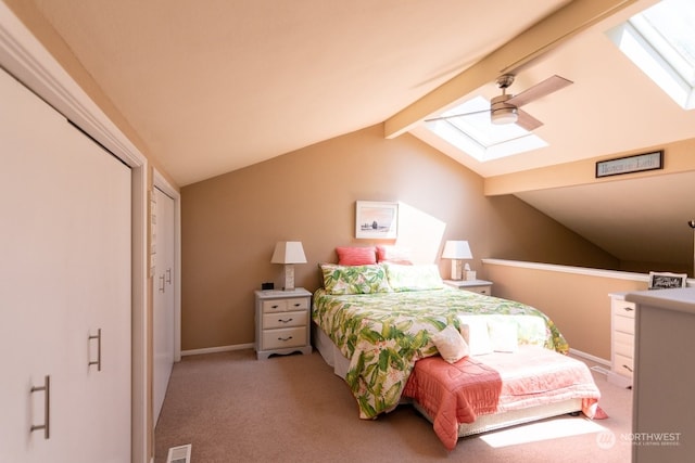 bedroom with ceiling fan, vaulted ceiling with skylight, a closet, and light carpet