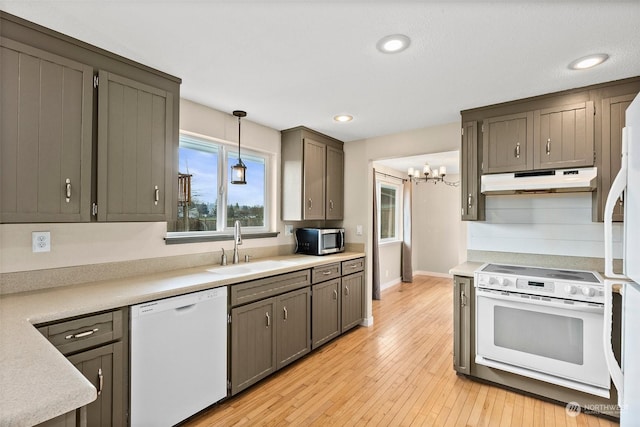 kitchen featuring sink, a chandelier, hanging light fixtures, light hardwood / wood-style floors, and white appliances