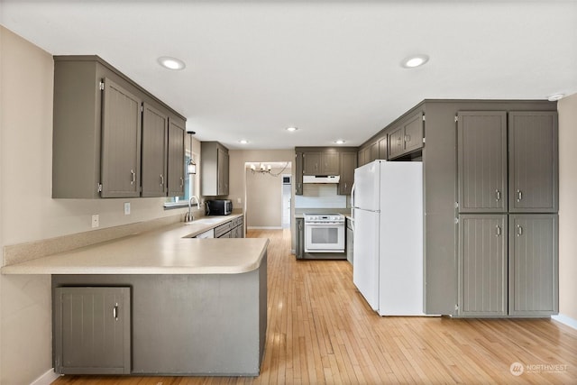 kitchen featuring sink, light hardwood / wood-style flooring, gray cabinets, kitchen peninsula, and white appliances