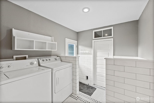 clothes washing area featuring tile walls and independent washer and dryer