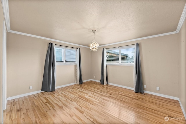 unfurnished room featuring ornamental molding, a notable chandelier, a wealth of natural light, and light hardwood / wood-style floors