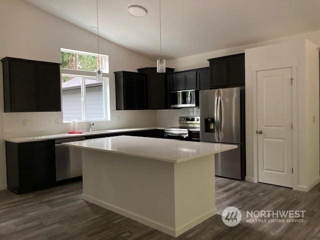 kitchen with pendant lighting, stainless steel appliances, a center island, and vaulted ceiling