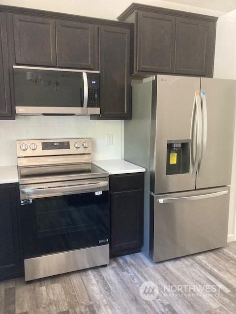 kitchen with stainless steel appliances, light hardwood / wood-style floors, and dark brown cabinets