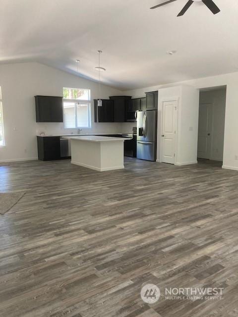 kitchen featuring ceiling fan, appliances with stainless steel finishes, dark hardwood / wood-style floors, a kitchen island, and vaulted ceiling