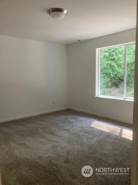 unfurnished room featuring dark colored carpet