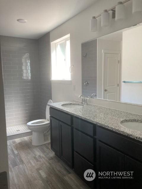 bathroom with vanity, hardwood / wood-style floors, toilet, and a tile shower