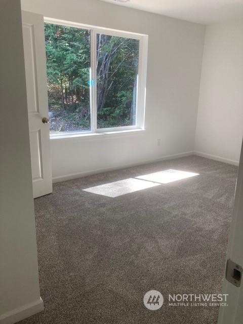 unfurnished room featuring dark colored carpet