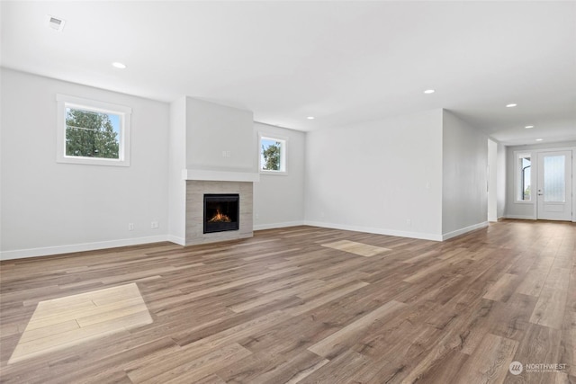 unfurnished living room with a tile fireplace and light wood-type flooring