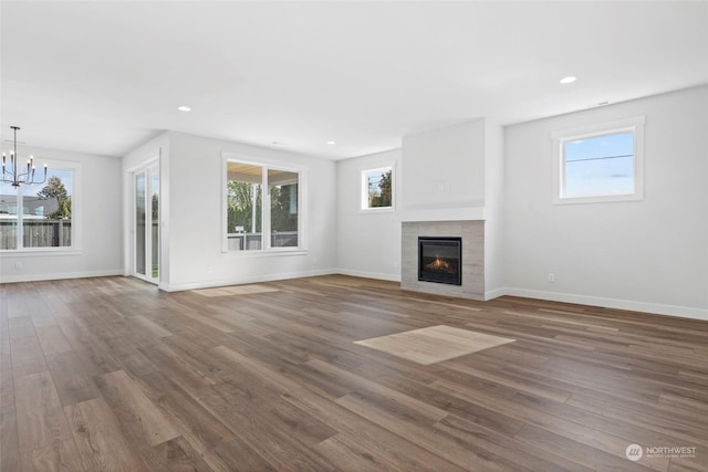 unfurnished living room featuring a tile fireplace, wood-type flooring, and a chandelier