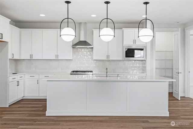 kitchen with built in microwave, white cabinetry, and wall chimney exhaust hood