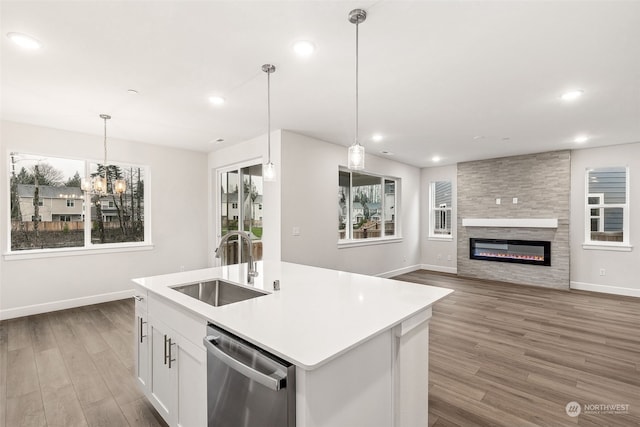 kitchen with sink, hanging light fixtures, white cabinets, a center island with sink, and stainless steel dishwasher