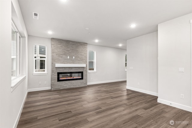 unfurnished living room with a large fireplace and dark hardwood / wood-style floors