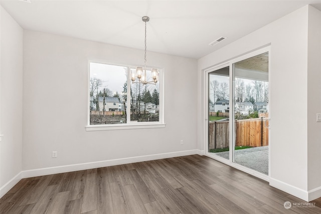 unfurnished dining area with hardwood / wood-style flooring, plenty of natural light, and an inviting chandelier