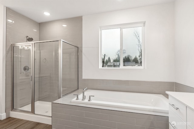 bathroom with vanity, wood-type flooring, and plus walk in shower