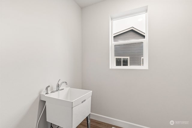 laundry room with hardwood / wood-style flooring and sink