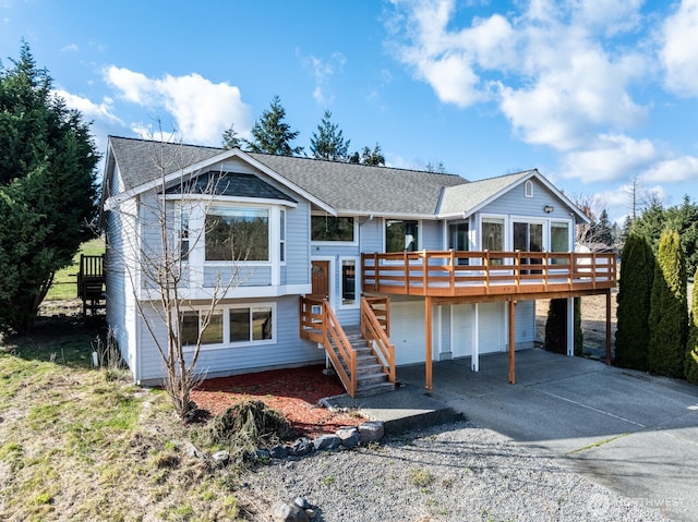 view of front of home with stairway, concrete driveway, roof with shingles, a garage, and a deck