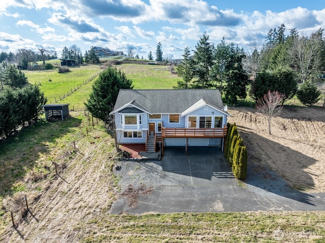 view of front of home featuring a deck, driveway, fence, a shingled roof, and a carport