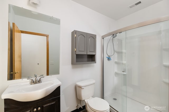 bathroom featuring vanity, toilet, visible vents, and a stall shower