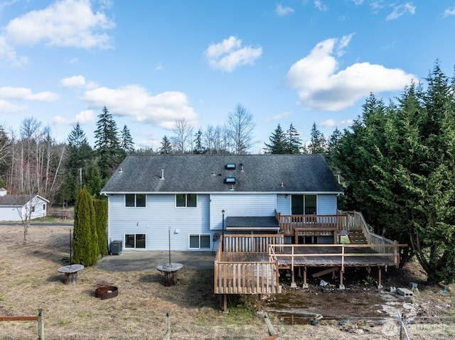 rear view of house featuring cooling unit, a shingled roof, and a deck