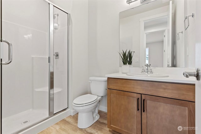 bathroom with vanity, hardwood / wood-style flooring, a shower with door, and toilet