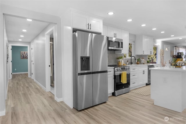 kitchen featuring sink, stainless steel appliances, light hardwood / wood-style floors, and white cabinets