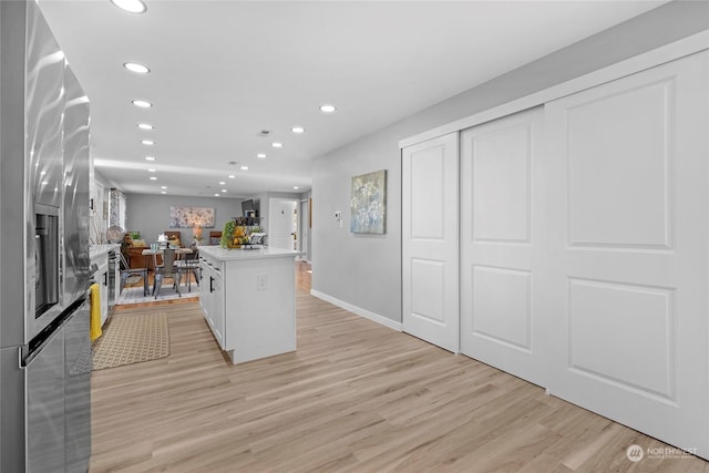 kitchen featuring stainless steel refrigerator with ice dispenser, white cabinetry, a kitchen island with sink, and light hardwood / wood-style floors