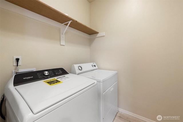 laundry area with light wood-type flooring, washer and dryer, laundry area, and baseboards