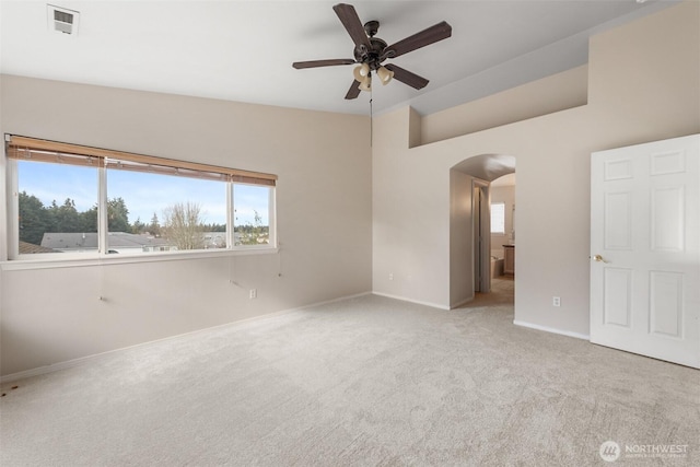 unfurnished bedroom featuring visible vents, arched walkways, baseboards, light colored carpet, and ceiling fan