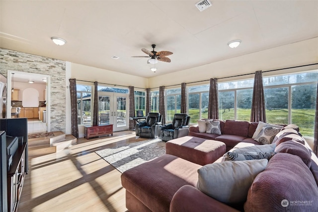 living room featuring plenty of natural light, french doors, ceiling fan, and light wood-type flooring