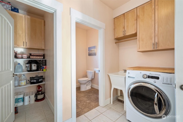 clothes washing area with light tile patterned floors, washer / dryer, and cabinets