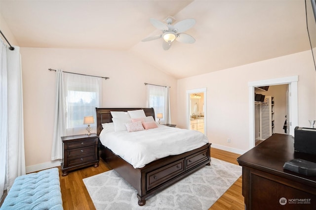 bedroom with lofted ceiling, ensuite bath, light hardwood / wood-style flooring, ceiling fan, and a walk in closet