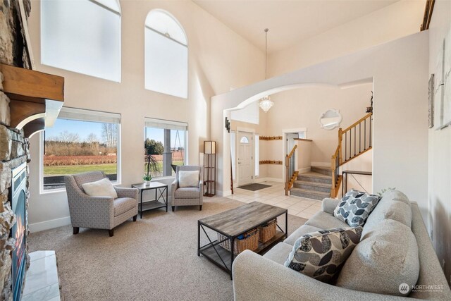 carpeted living room with a high ceiling and a stone fireplace