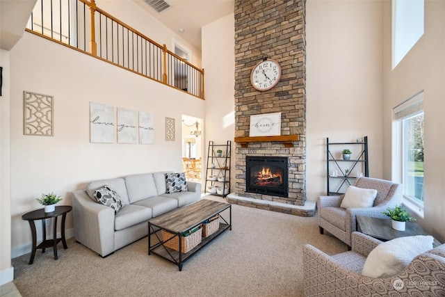 carpeted living room featuring a stone fireplace and a towering ceiling