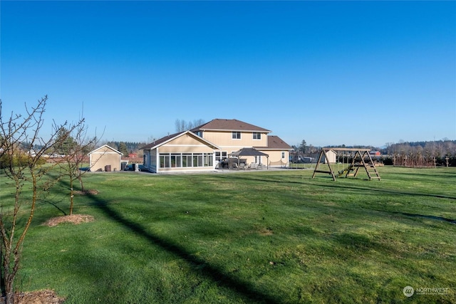 rear view of property featuring a yard, a sunroom, and a playground