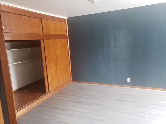 unfurnished bedroom with light wood-type flooring and a closet