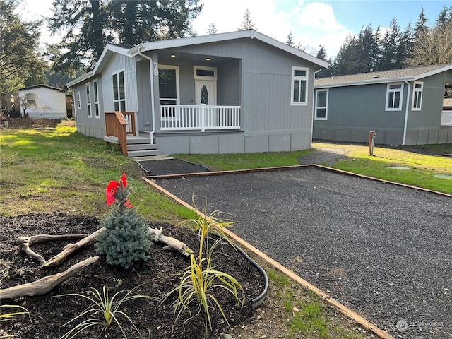 manufactured / mobile home with covered porch and a front lawn