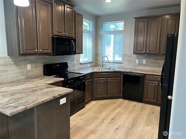 kitchen featuring dark brown cabinetry, sink, light wood-type flooring, decorative backsplash, and black appliances