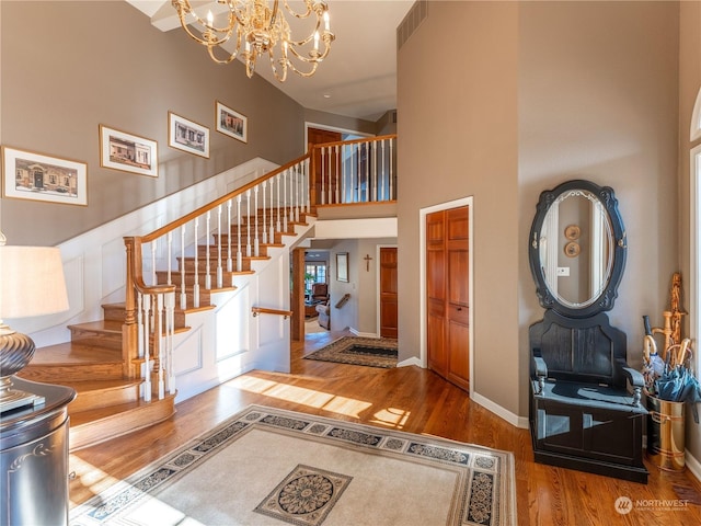 entryway featuring a towering ceiling, hardwood / wood-style floors, and an inviting chandelier