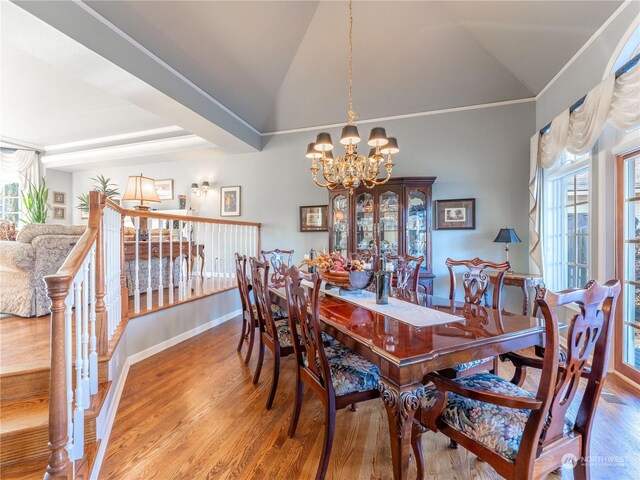 dining area with hardwood / wood-style flooring, a chandelier, and vaulted ceiling