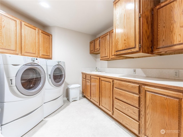 clothes washing area featuring independent washer and dryer, cabinets, and sink