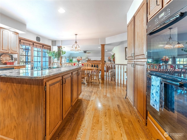 kitchen with pendant lighting, light hardwood / wood-style flooring, a center island, light stone counters, and french doors