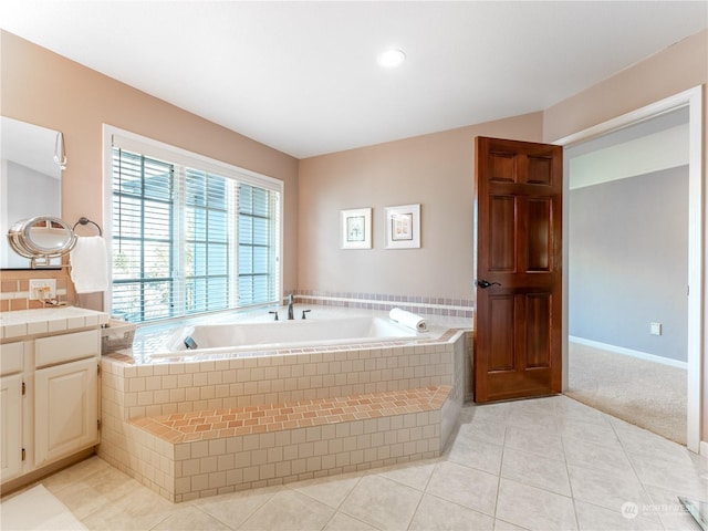 bathroom with a relaxing tiled tub, tile patterned floors, and vanity