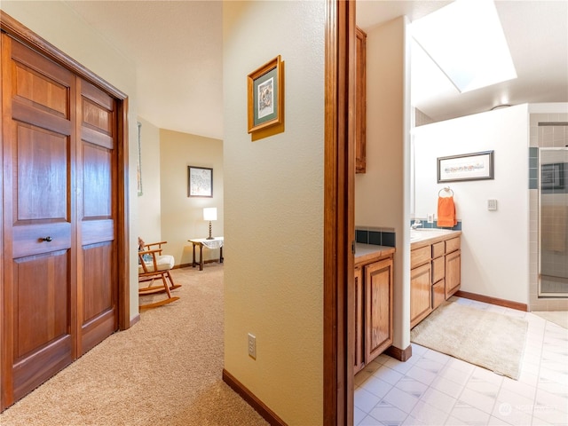 hall with sink, light carpet, and a skylight