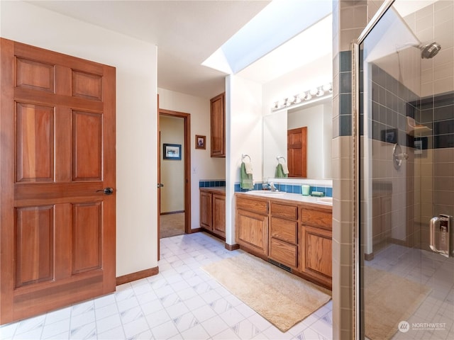 bathroom with vanity, an enclosed shower, and a skylight