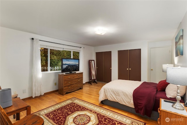 bedroom with two closets and light hardwood / wood-style flooring