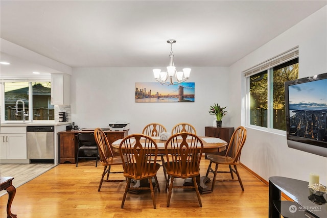 dining space with sink, a notable chandelier, and light wood-type flooring