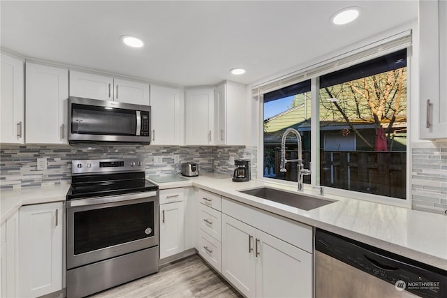 kitchen with tasteful backsplash, appliances with stainless steel finishes, sink, and white cabinets