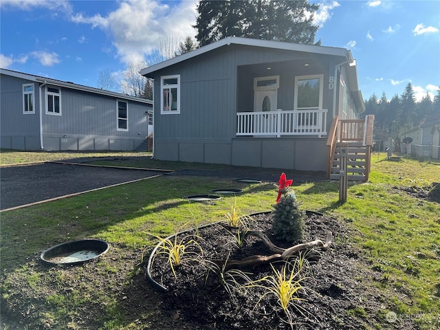 view of side of home with a yard and covered porch