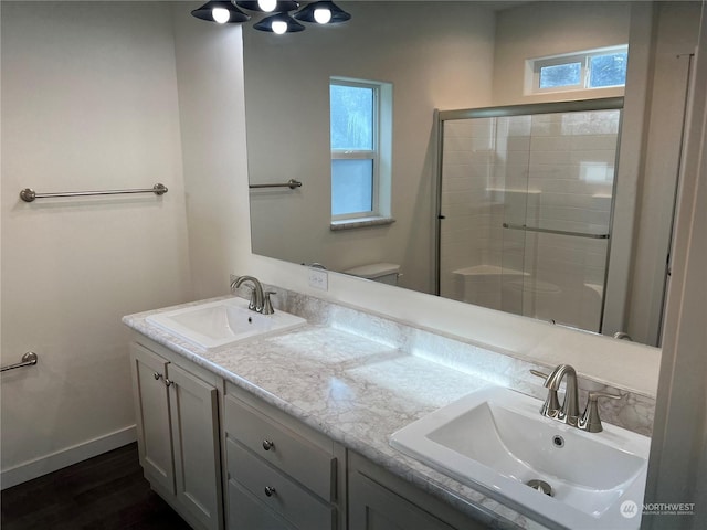 bathroom featuring wood-type flooring, toilet, a shower with shower door, and vanity